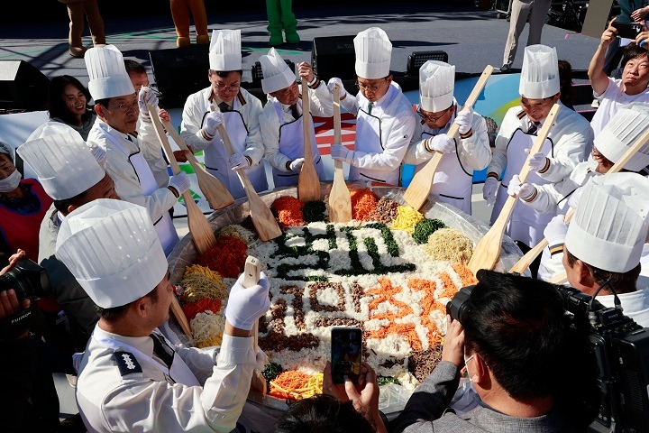2023.벌교 꼬막축제_ 대형 꼬막 비빔밥을 비비고 있다.JPG